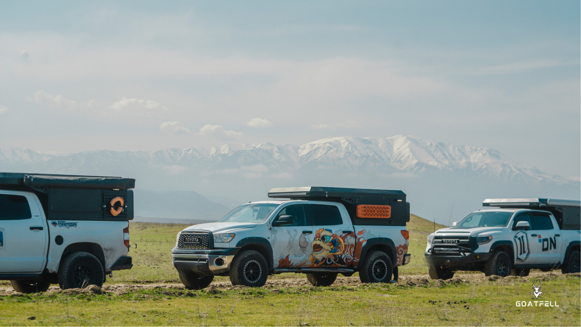 Demountable camper truck on grass with mountains in the background 